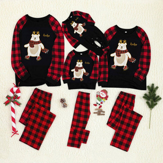 Kids' Christmas pajamas with a black long-sleeve top featuring a cartoon bear in a plaid scarf and ice skates, paired with red and black plaid pants.