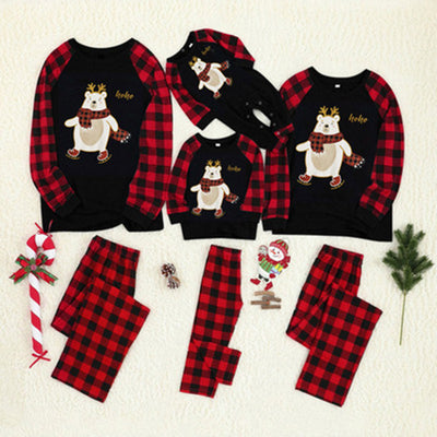 Kids' Christmas pajamas with a black long-sleeve top featuring a cartoon bear in a plaid scarf and ice skates, paired with red and black plaid pants.