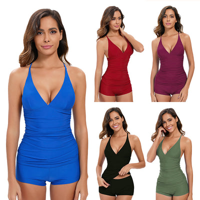 Woman wearing a black two-piece tankini swimsuit with a deep V-neck halter top and ruched sides, paired with boy short bottoms.