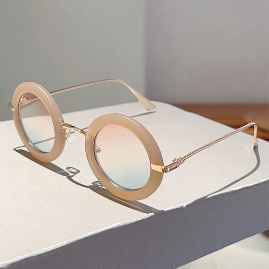 Small frame oval fashion sunglasses with black frames and vibrant orange lenses, held by a hand. - Image 28