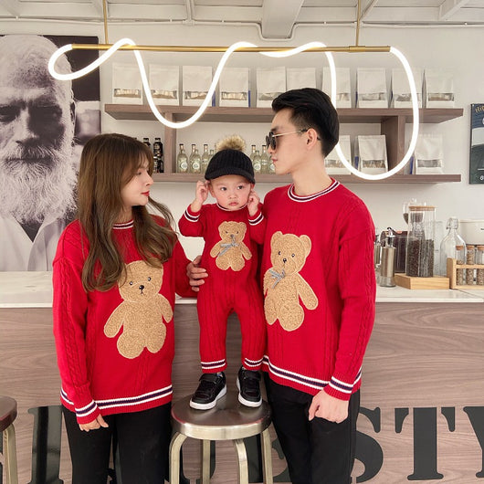 Family of three wearing matching red cable-knit sweaters with a brown teddy bear appliqué and striped trim. - Image 11