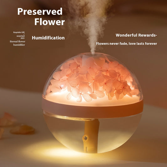 Pink round mini humidifier with clear dome, decorative pink flowers, and a light-up base, ideal for desktop or bedroom.