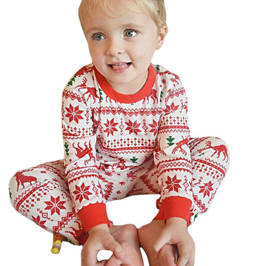 Family wearing matching white and red Christmas pajamas with elk and snowflake patterns, including a baby and a dog. - Image 10