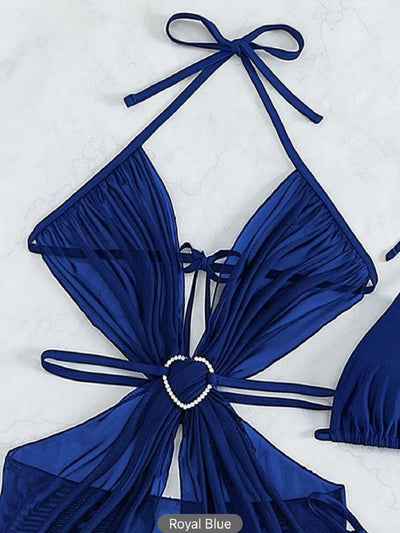 White three-piece halter neck bikini and sheer cover-up set with a heart-shaped embellishment, laid flat on wood. - Image 17