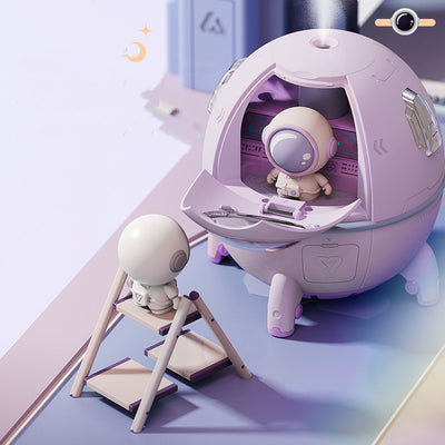 White USB astronaut humidifier shaped like a rocket, emitting mist, with a small astronaut figure inside a clear dome.