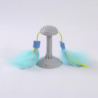 Gray suction cup cat toy with a textured top and two blue and yellow feathered wands attached by green cords.
