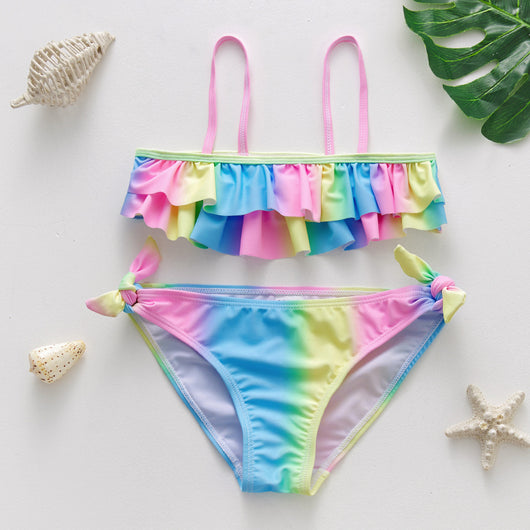Children's rainbow tie-dye bikini set with a ruffled top and side-tie bottoms, perfect for summer swimming.