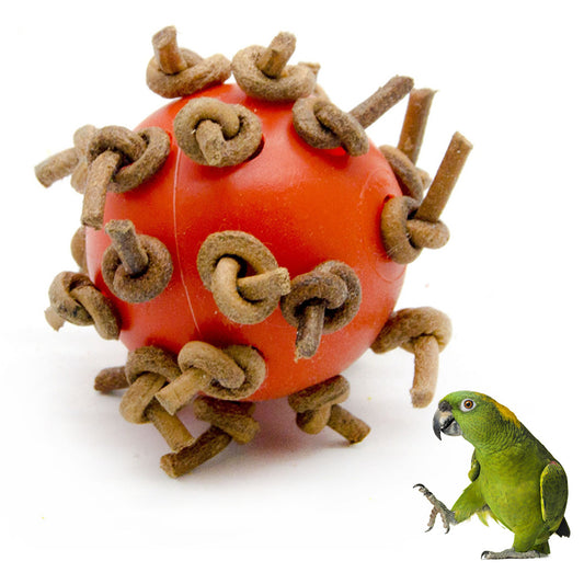 Red plastic interactive chewing ball with brown leather rope knots, next to a green parrot.