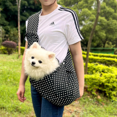 Person in white hoodie carrying a happy white dog in a navy blue pet sling bag outdoors. - Image 50