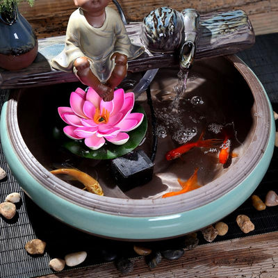 Ceramic flowing water ornament with a meditating monk figurine, small plant, and misting humidifier in a teal and brown bowl. - Image 3