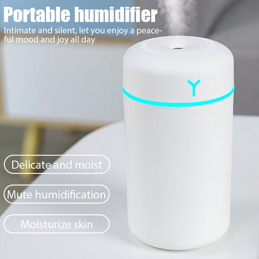 Pink portable humidifier with a blue LED light band, emitting fine mist, on a white pedestal.