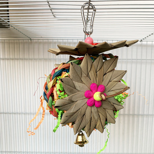 Colorful parrot chew toy made from natural fibers, featuring a woven ball, leaf-like accents, a bell, and a carabiner clip. - Image 4