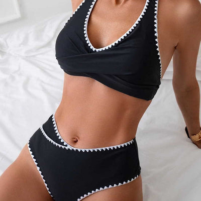 Black two-piece swimsuit with white scalloped trim, featuring a halter neck wrap-front top and high-waisted bottoms.