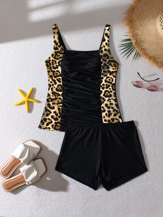 Women's black and leopard print tankini swimsuit with ruched top and swim shorts, modeled on a beach. - Image 17