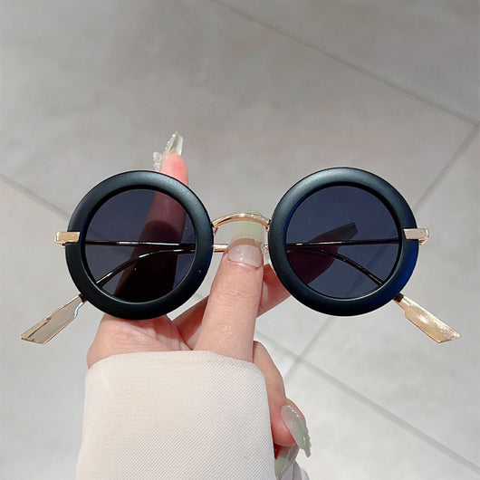 Small frame oval fashion sunglasses with black frames and vibrant orange lenses, held by a hand. - Image 9