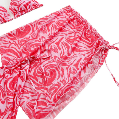 Women's three-piece swimsuit in red and orange abstract swirl print, featuring a halter bikini top, tie-side bottoms, and a ruched mini skirt. - Image 5
