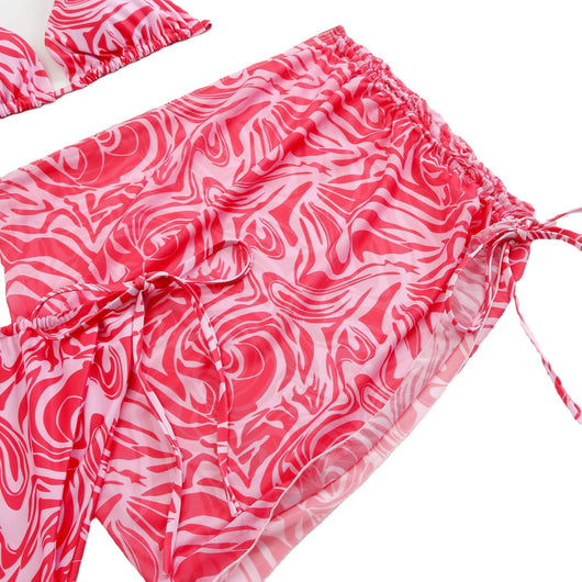 Women's three-piece swimsuit in red and orange abstract swirl print, featuring a halter bikini top, tie-side bottoms, and a ruched mini skirt. - Image 5