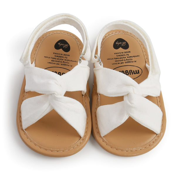 Black baby sandals with knotted cross straps and a matching black floral headband on a white background. - Image 5