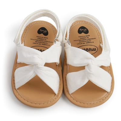 Black baby sandals with knotted cross straps and a matching black floral headband on a white background. - Image 5