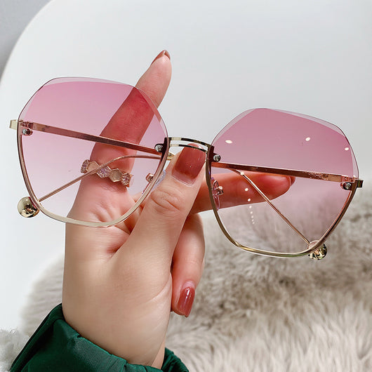 Elegant fashion sunglasses with gold metal frames and pink gradient lenses, held against a white case. - Image 7
