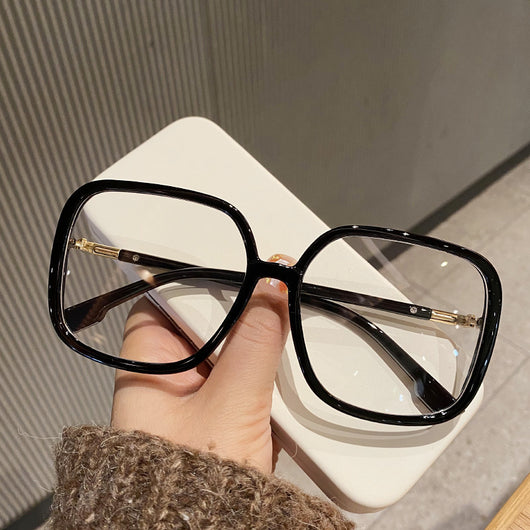 Black oversized square anti-blue light glasses with clear resin lenses and gold metal frame details, held by a hand. - Image 8