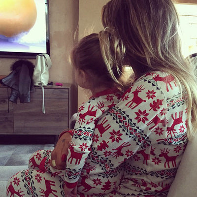 Family of four wearing matching red and white Christmas pajamas with reindeer and snowflake patterns, sitting with gifts. - Image 9