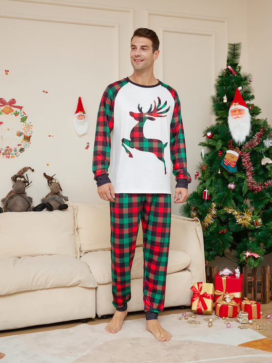 Two children in matching red and green plaid Christmas pajamas with a reindeer graphic, standing by a Christmas tree. - Image 9