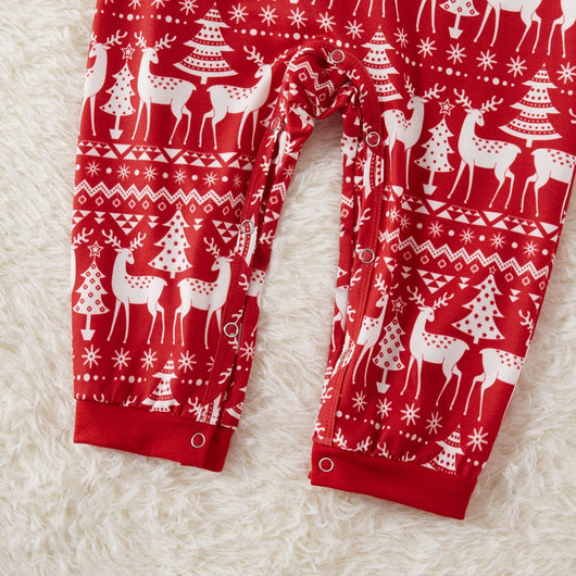 Family of four wearing matching red Christmas pajamas with white reindeer and tree patterns, standing by a decorated tree. - Image 10