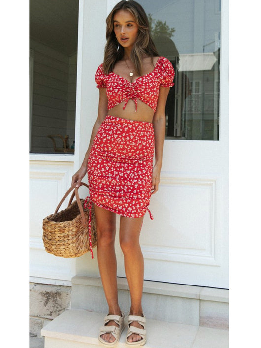 Smiling woman in a red floral print crop top and matching ruched mini skirt with side ties. - Image 6