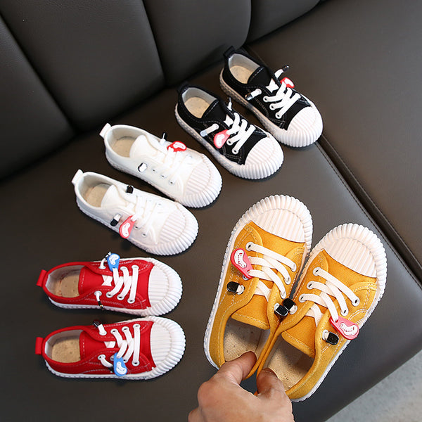 Pair of black canvas children's shoes with white laces and white rubber toe cap and sole.