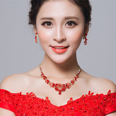 Red rhinestone bridal jewelry set featuring a floral necklace and matching dangle earrings on a model.