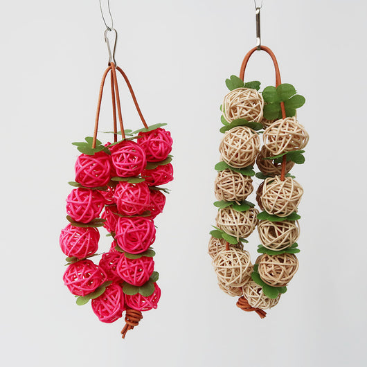 Pink woven rattan ball parrot chew toy with green leaf accents, hanging from a metal hook. - Image 5