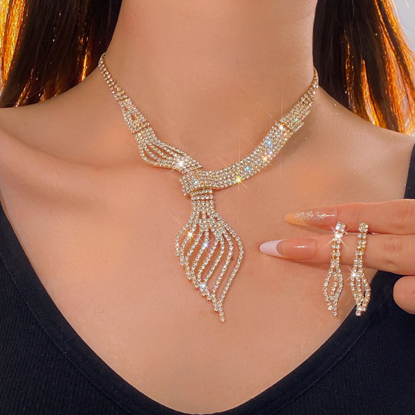 Gold-tone rhinestone necklace and matching dangle earrings set. The necklace features a multi-strand, leaf-like design.