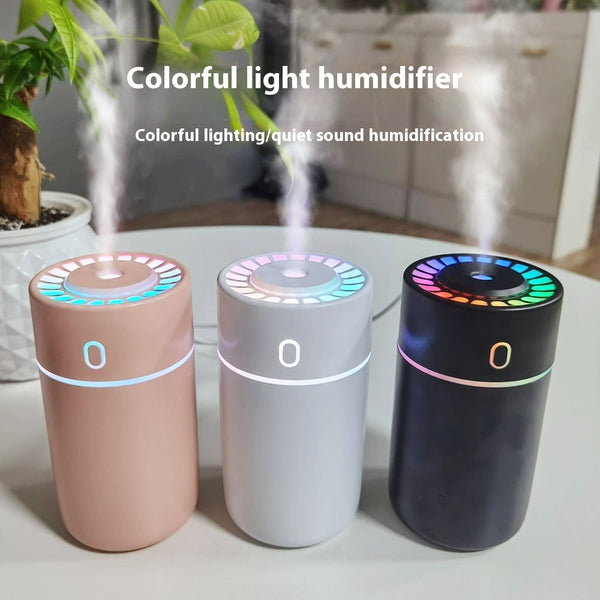 Pink cylindrical humidifier with a colorful LED light ring on top and a blue-green light band around its middle.
