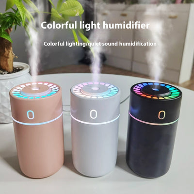 Pink cylindrical humidifier with a colorful LED light ring on top and a blue-green light band around its middle.