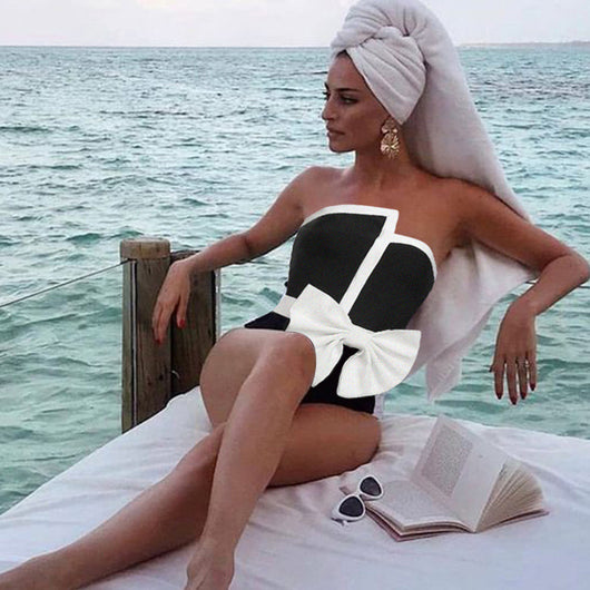 Black and white color-block one-piece swimsuit with an irregular tube top and a large white bow, paired with a matching pencil skirt.