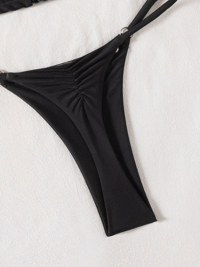 Black tie-front bikini swimsuit with silver grommets on the triangle top and a ruched thong bottom, laid flat. - Image 17