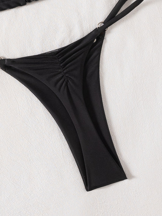 Black tie-front bikini swimsuit with silver grommets on the triangle top and a ruched thong bottom, laid flat. - Image 17