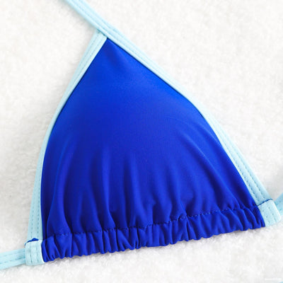 Royal blue two-piece bikini with light blue trim and tie straps, laid flat on a white textured surface. - Image 29