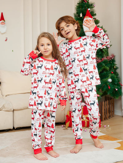 Young girl in white Christmas pajamas with red deer and tree print, red trim, standing by a decorated tree. - Image 4