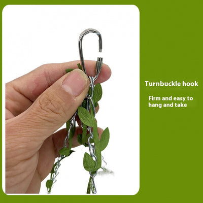 Small forest style plush bird hammock in green and yellow, hanging from a chain with artificial leaves. - Image 4