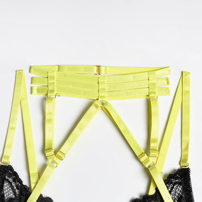 Woman in a neon yellow strappy harness lingerie set over a black lace bra and thong, sitting on a white bed. - Image 17