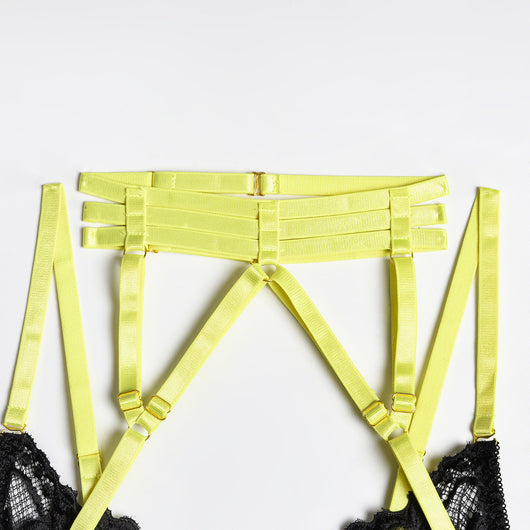 Woman in a neon yellow strappy harness lingerie set over a black lace bra and thong, sitting on a white bed. - Image 17