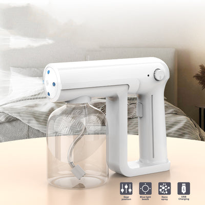 Black wireless alcohol blue light disinfection spray gun with clear reservoir, actively misting, on a marble surface. - Image 5