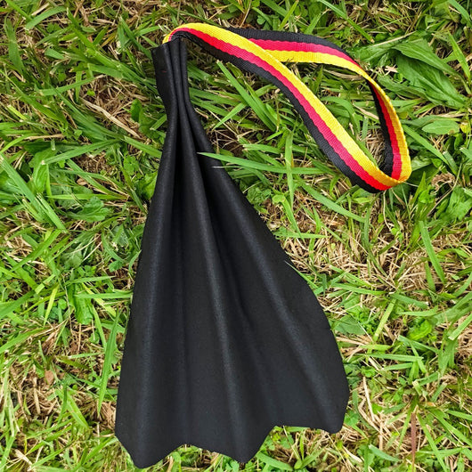 German Shepherd holding a black leather dog bite rag with a red, yellow, and black striped handle. - Image 11
