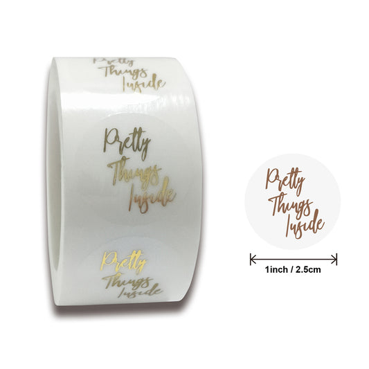 Roll of transparent round adhesive stickers with gold foil "Thank You!" text in a decorative script font.