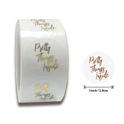 Roll of transparent round adhesive stickers with gold foil "Thank You!" text in a decorative script font.