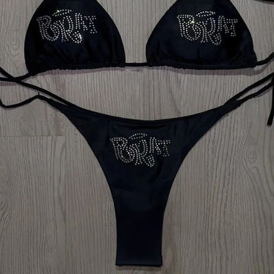 Black halter bikini with rhinestone 'BRAT' lettering on triangle top and tie-side bottom, displayed on white faux fur. - Image 2