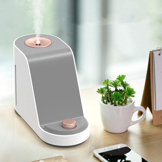 White and gray trapezoidal humidifier with a rose gold top mist outlet and control knob on a wooden desk. - Image 7