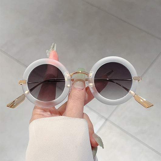 Small frame oval fashion sunglasses with black frames and vibrant orange lenses, held by a hand. - Image 11